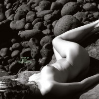 Nude Model Laying Prone On Rocks - Naked Girl, Nude Amateur , Black And White Photo, Puffy Areolas, Artistic Implied Nude, Curvy Feminine Hips, Photo Taken From Above And Slightly Behind The Model, Round And Firm, Artistic On The Rocks, Left Naked On The Rocks, Legs Are Slightly Bent And Turned Away From Camera